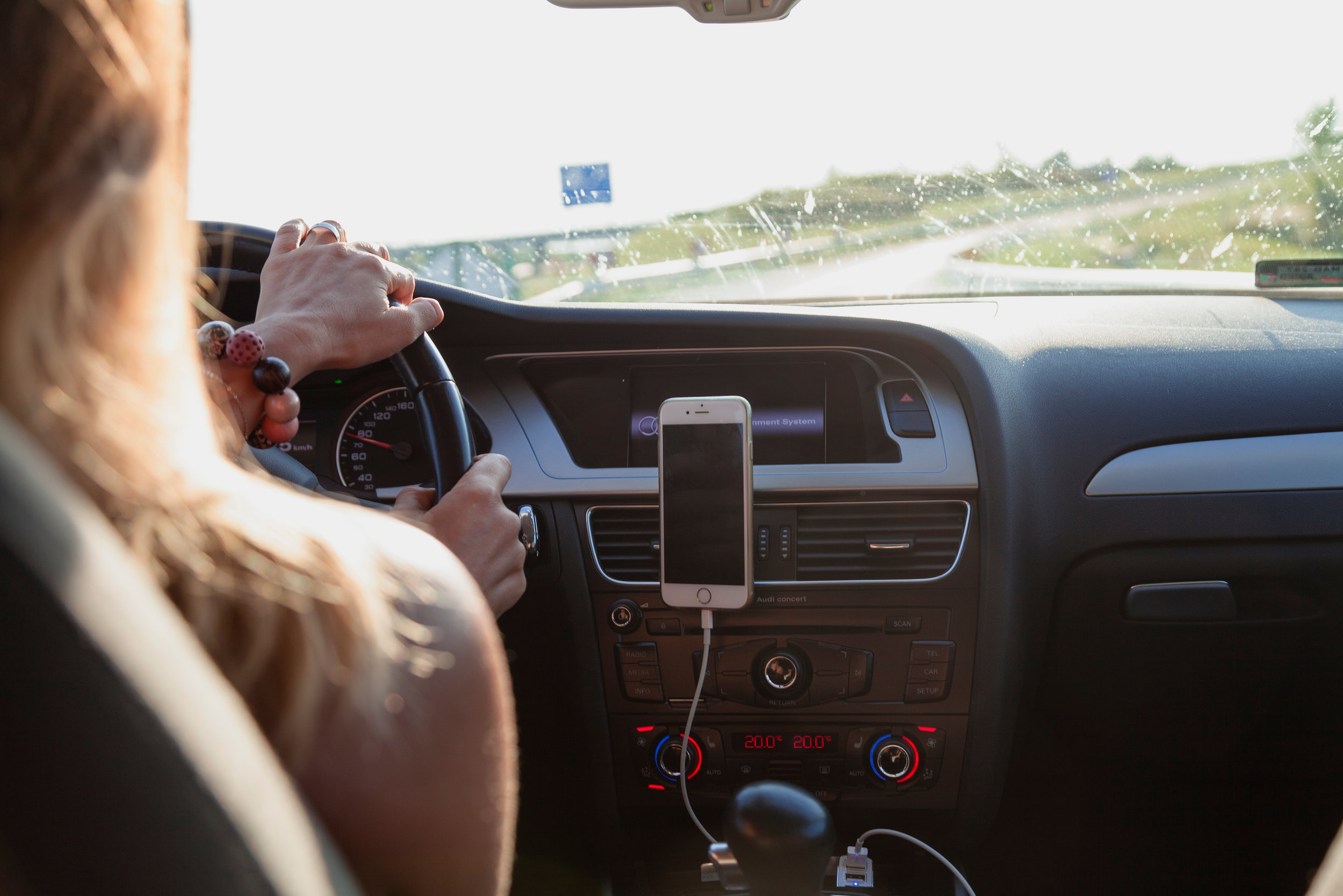 woman driving a car with her cell phone plugged in